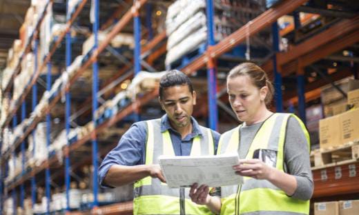 Two warehouse supervisors reviewing operations on a tablet